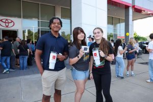 three students show promotional items